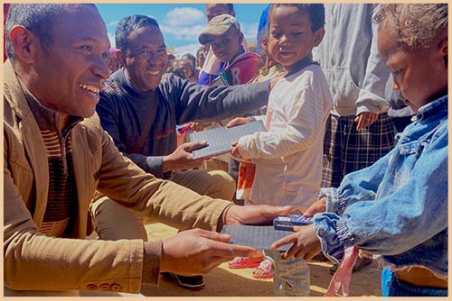 Nomena distributing school supplies to children